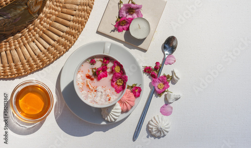 Layout with pink moon milk, flowers, honey and a summer straw hat. Copy of the space