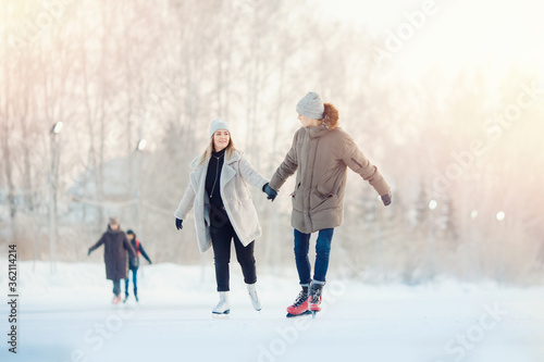 Happy young couple in sunny winter nature ice skating