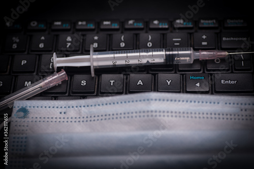A black keyboard with syringe .with the phrase stay at home