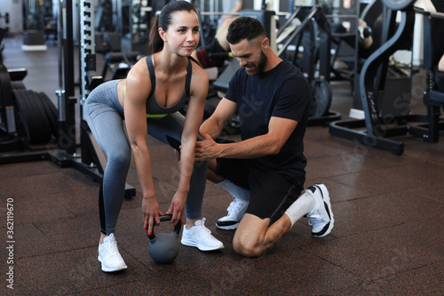 Fitness instructor exercising with his client at the gym.