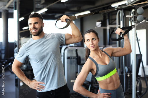 Young couple on body training with trx in gym.