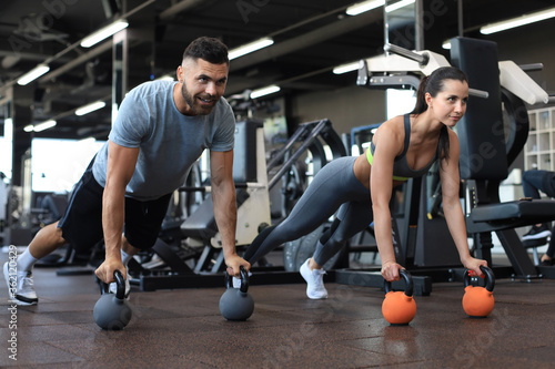 Fototapeta Naklejka Na Ścianę i Meble -  Sporty man and woman doing push-up in a gym.