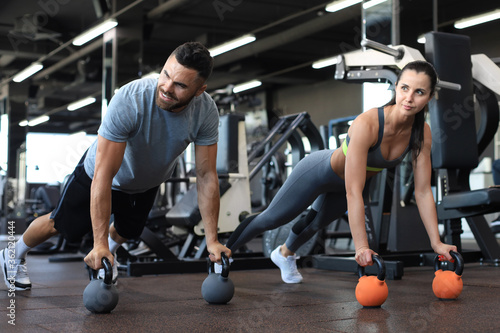 Sporty man and woman doing push-up in a gym.