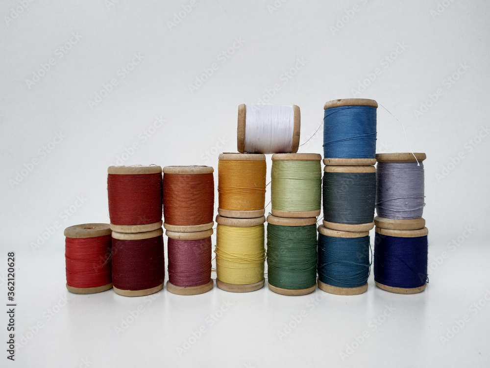 Colored spools of sewing thread on a white background. Sewing masks, clothes, multi colored rainbow colored threads. Small spools of colored thread stand in several rows, a wall of spools of thread Colored spools of sewing thread on a white background. Sewing masks, clothes, multi colored rainbow colored threads. Small spools of colored thread stand in several rows, a wall of spools of thread