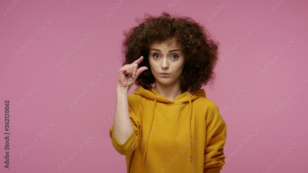 Too small! Girl afro hairstyle in hoodie showing a little bit sign, looking with imploring grimace and disappointed in size, need some more, gesturing minimum. studio shot isolated on pink background Too small! Girl afro hairstyle in hoodie showing a little bit sign, looking with imploring grimace and disappointed in size, need some more, gesturing minimum. studio shot isolated on pink background