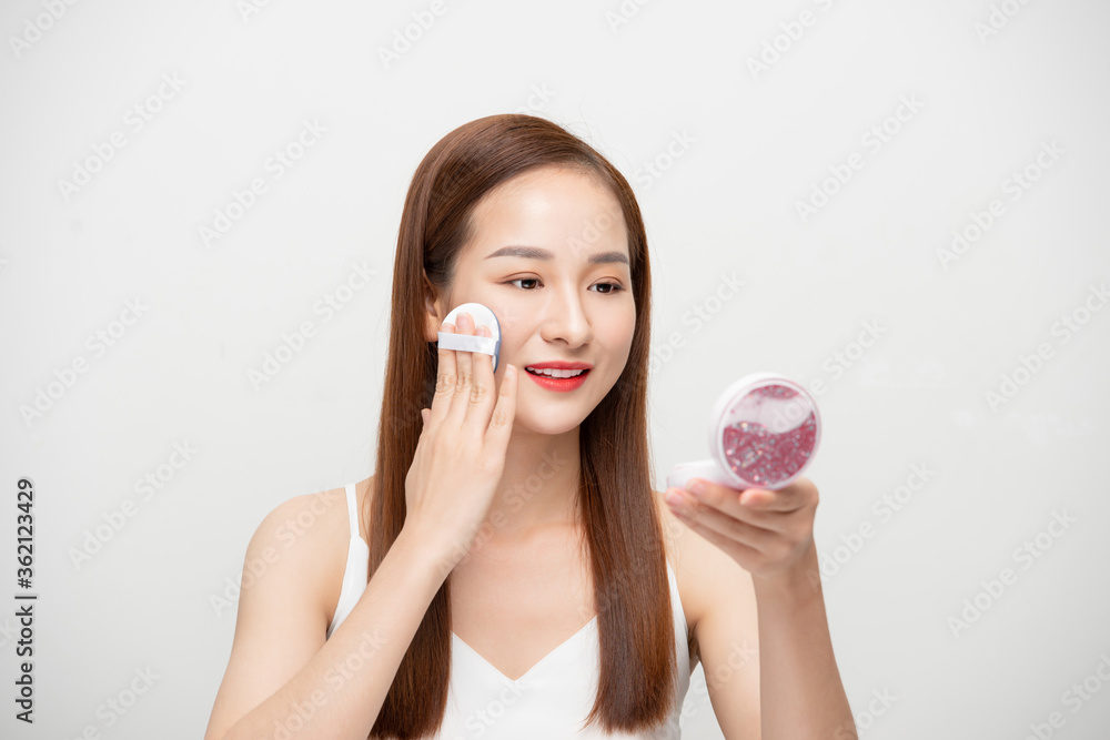 Beautiful young Asian woman applying powder over white background. Beautiful young Asian woman applying powder over white background.