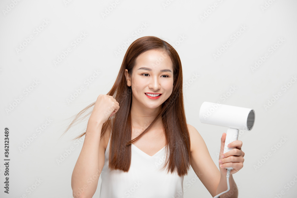 Beautiful girl drying her hair with hairdryer over white background. Beautiful girl drying her hair with hairdryer over white background.