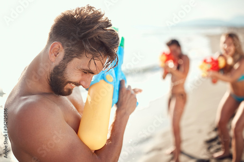 two women sprinkle a guy with water guns