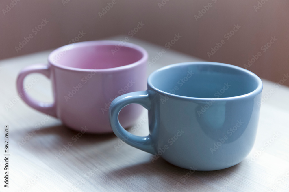 Two cups on a wooden table. Blue and pink. Two cups on a wooden table. Blue and pink.