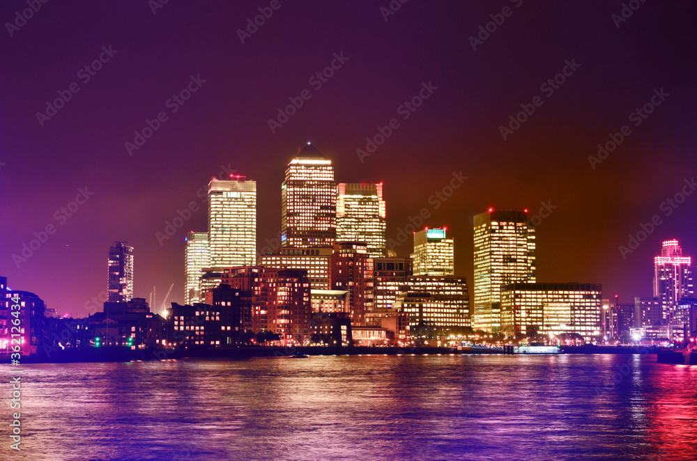 London at night and river Thames. High buildings with luminous windows.