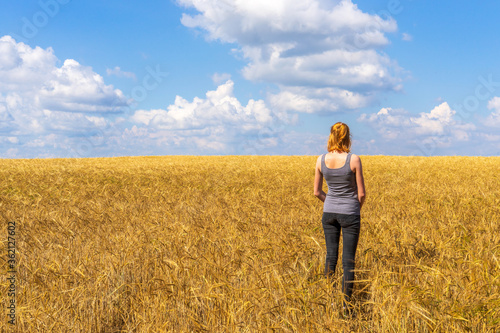 Tourist tween girl admiring picturesque rural landscape of golden ripe rye field and blue sky in summer sunny day. Travelling to clean places of Earth or beauty of nature discovering concept © Tatyana_Andreyeva