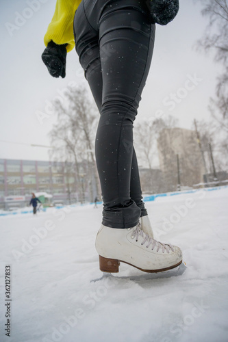 Figure skating on the street at an outdoor ice rink. Close-up of the skater's legs on ice. A woman goes in for sports.