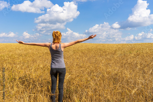 Tourist tween girl admiring picturesque rural landscape of golden ripe rye field and blue sky in summer sunny day. Travelling to clean places of Earth or beauty of nature discovering concept © Tatyana_Andreyeva