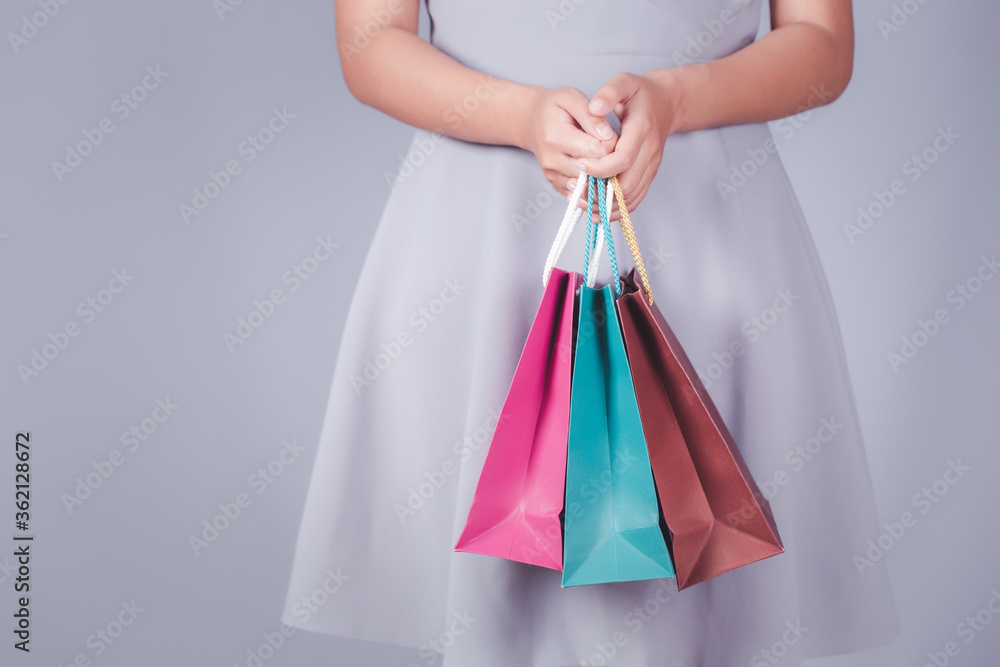 Female holding multicolored shopping bags gray background.