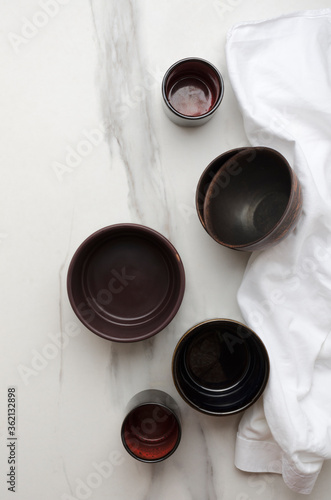 Vertical image.Top view of clay bowels and cups on the white marble table, white napkin