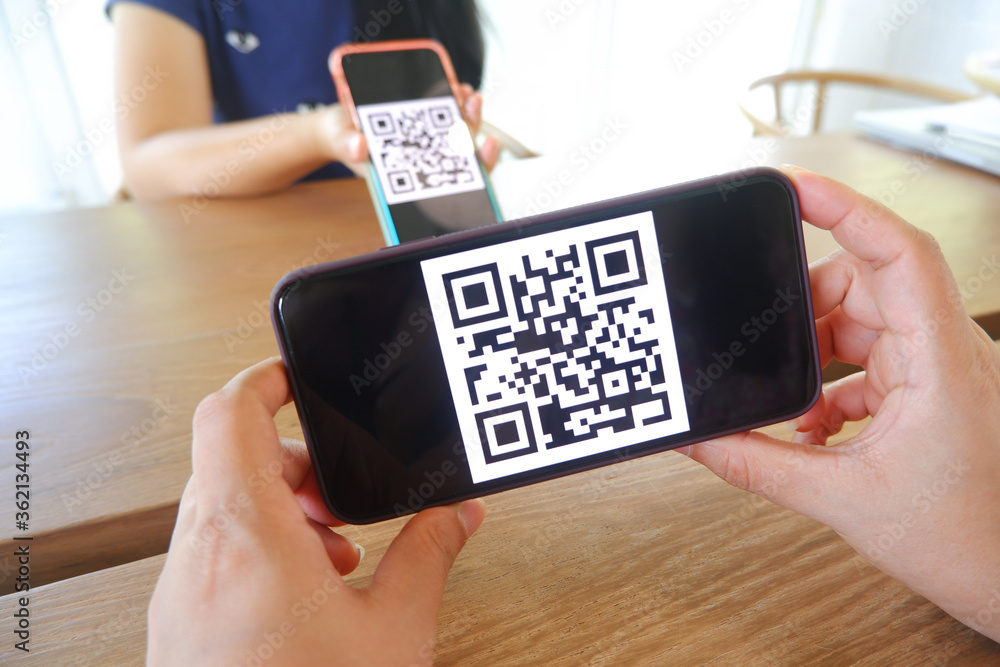 Women's hand uses a mobile phone application to scan QR codes in stores