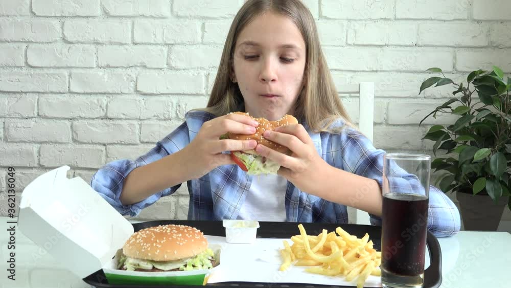 Kid Eating Fast Food, Child Eats Hamburger in Restaurant, Teenager Blonde Girl Drinking Juice Kid Eating Fast Food, Child Eats Hamburger in Restaurant, Teenager Blonde Girl Drinking Juice