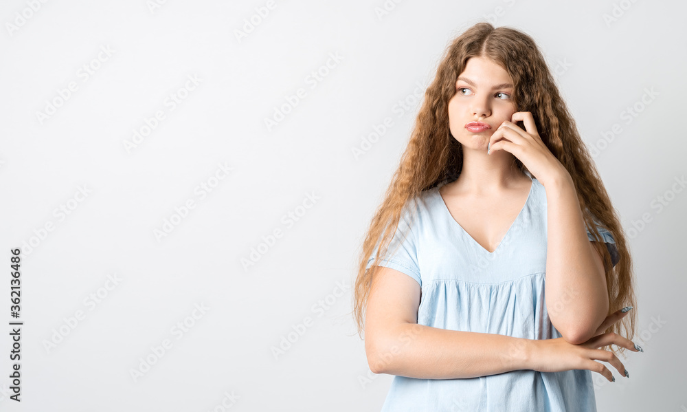 Photo of Pensive European young woman with curly long hair, looking up having pensive expression. Isolated over white background. Copy space for your text Photo of Pensive European young woman with curly long hair, looking up having pensive expression. Isolated over white background. Copy space for your text