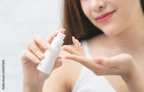 Smiling young woman applies cream beauty care on her hands.