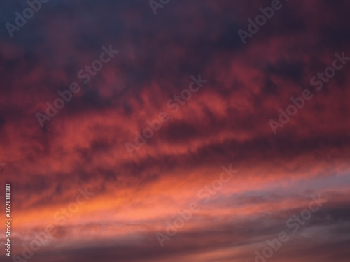 Red dramatic evening сumulus clouds in the sky. Colorful cloudy sky at sunset. Sky texture, abstract nature background