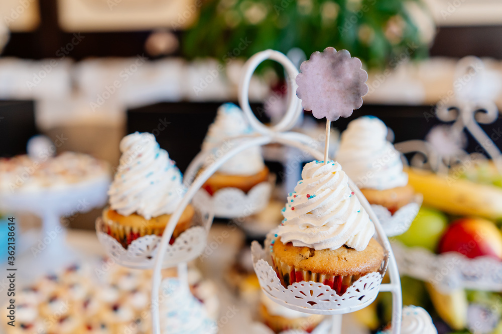 Cupcakes with cream and sprinkles on stands and labels for labeling