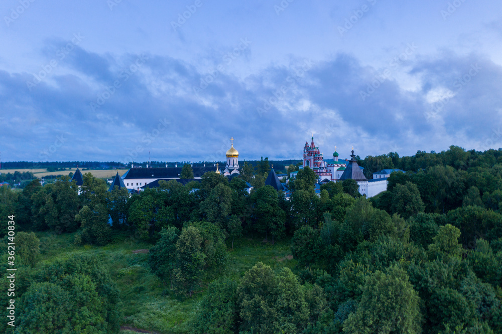 white stone fortress at dawn on a green hill filmed from a drone