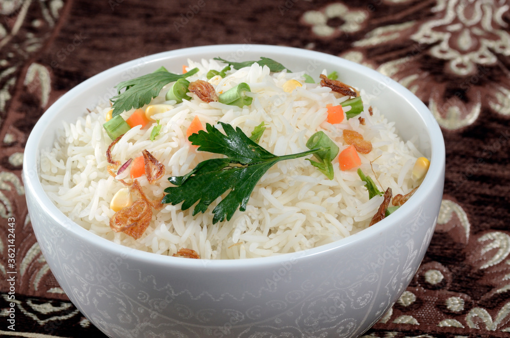 bowl of cooked basmati garnished with chopped vegetables in even lighting bowl of cooked basmati garnished with chopped vegetables in even lighting