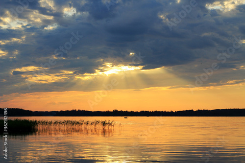 Billede på lærred People vacationing in nature or fishermen go by boat on the lake during a beautiful sunset