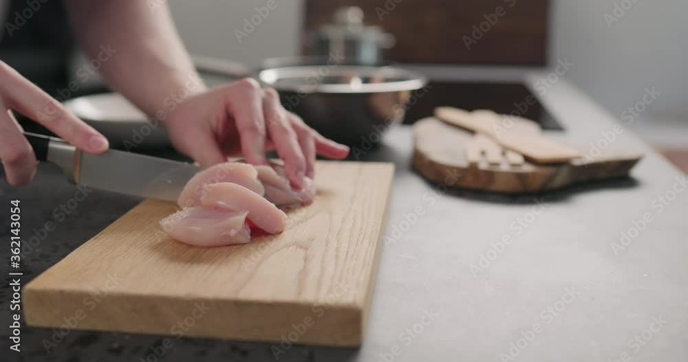 Slow motion man hands slicing chicken fillet on oak board Slow motion man hands slicing chicken fillet on oak board