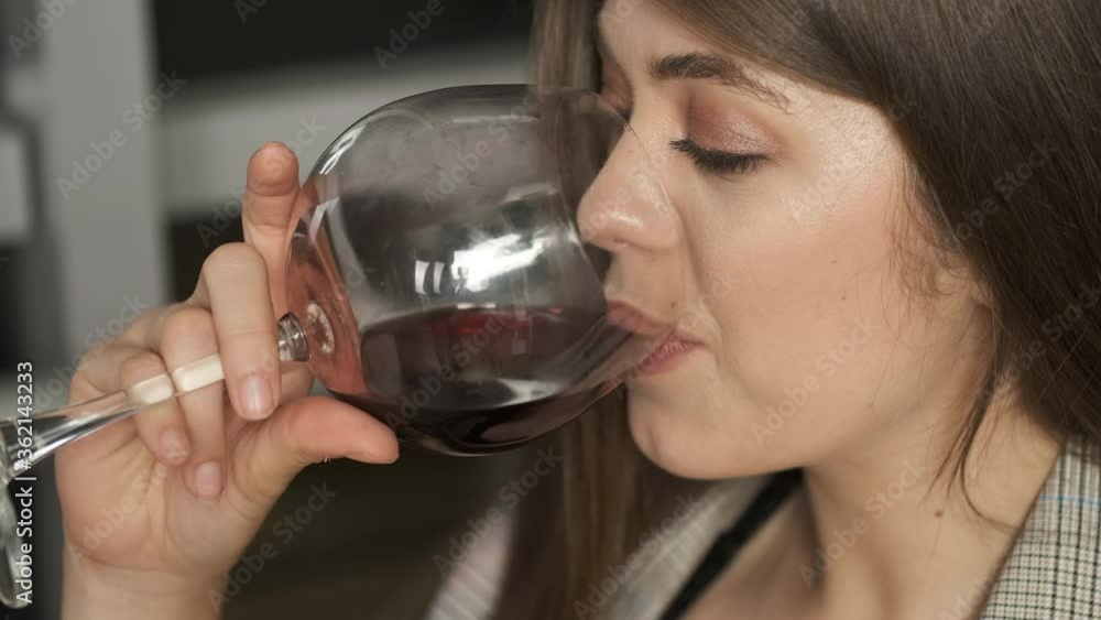 Beautiful girl of Caucasian appearance with long hair sitting by the panoramic window reads a book holding a glass of red wine and enjoys the night city Beautiful girl of Caucasian appearance with long hair sitting by the panoramic window reads a book holding a glass of red wine and enjoys the night city