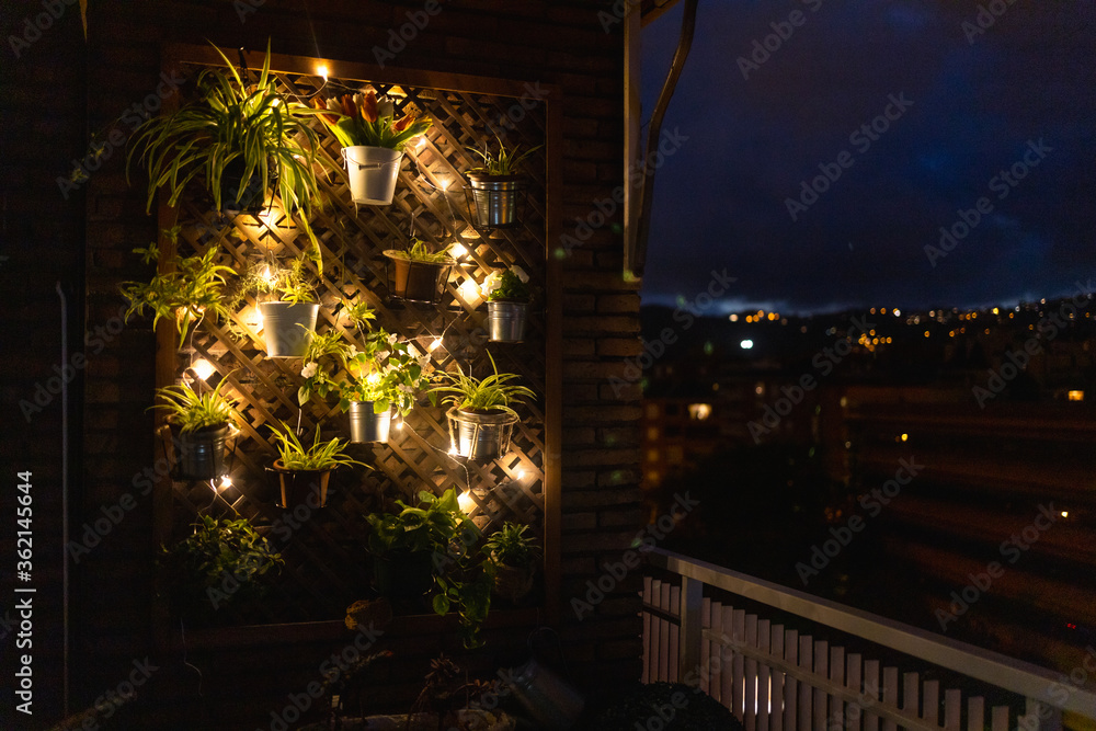 Vertical garden with fairy lights in the city during night time.  Stock photo of a city garden iluminated with led lights showing the cityscape. Focus selective.