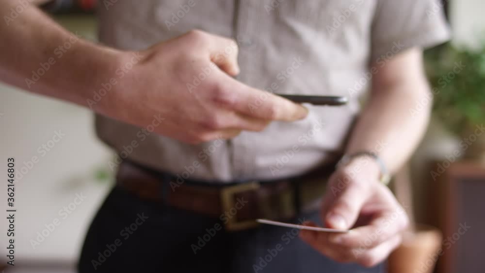 Man takes a photo of his credit card with smartphone to make an online purchase Man takes a photo of his credit card with smartphone to make an online purchase