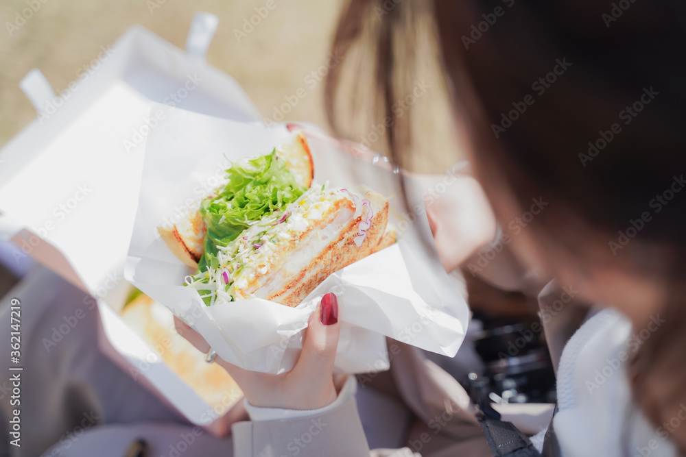 サンドイッチを手に持つ女性