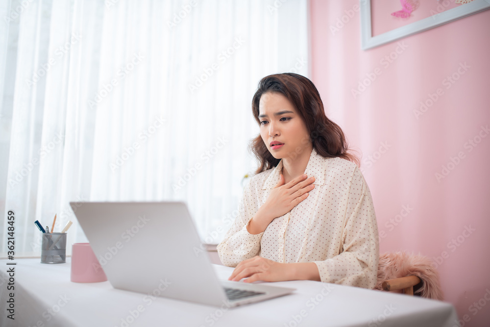 Asian beautiful woman sick with feeling pain in the chest while working with a laptop Asian beautiful woman sick with feeling pain in the chest while working with a laptop