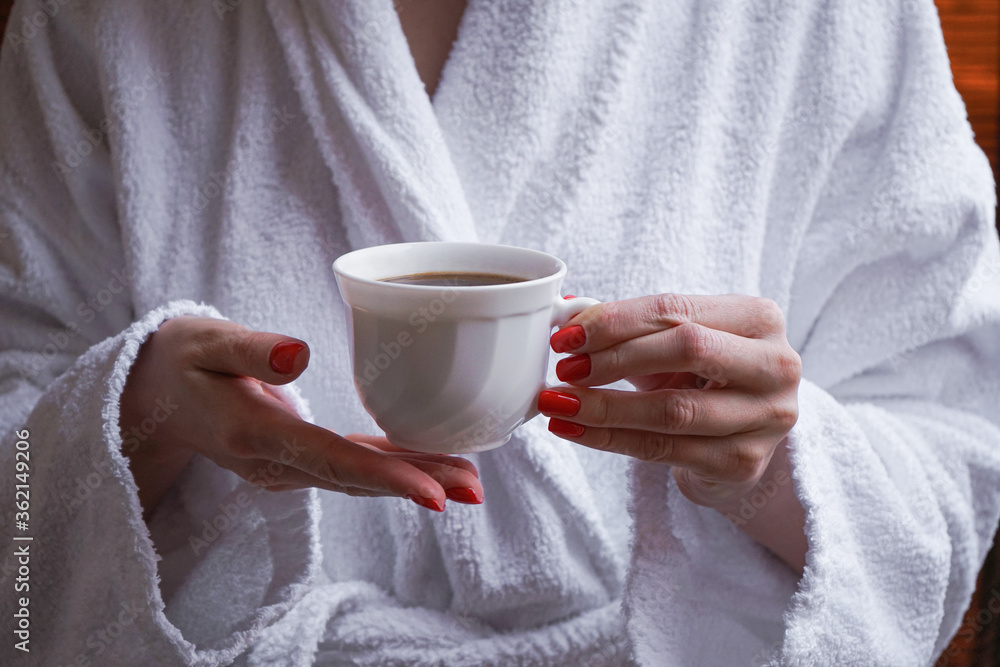 The concept of rest in a hotel. A cup in the hands of a girl in a white coat. The concept of rest in a hotel. A cup in the hands of a girl in a white coat.