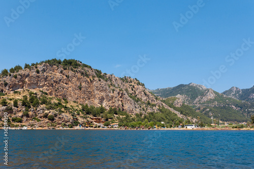 View from the sea on a tourist village on the background of a brown mountain