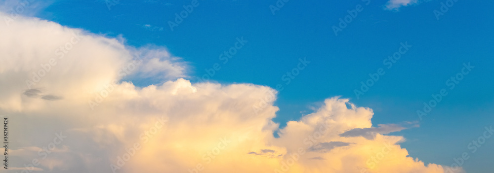 Panorama of bright clouds in the blue sky at sunset, which are placed horizontally