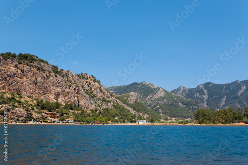 View from the sea on a tourist village on the background of a brown mountain © Vladislav