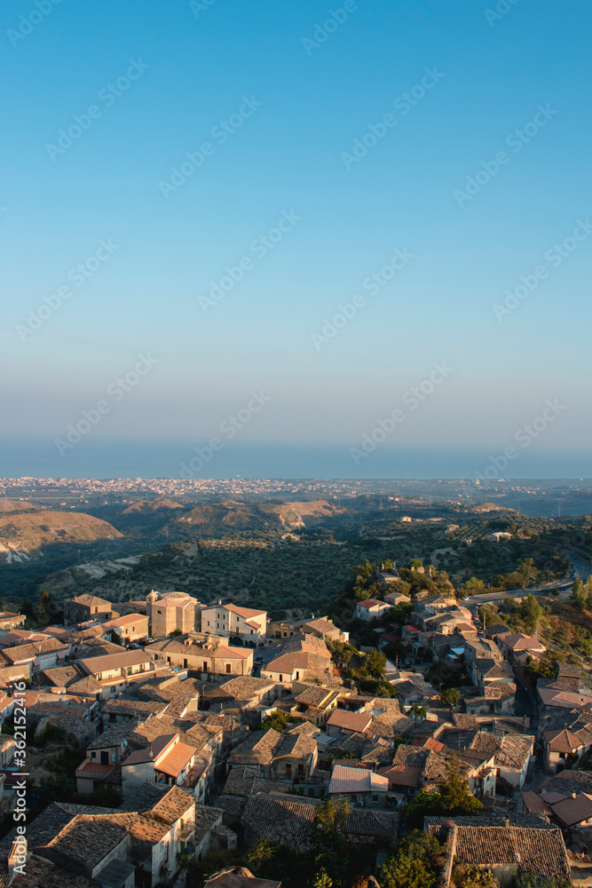 aerial view of Gerace, Calabria (Italy) at the sunset on a hill. A south italian village. it is possible see the stone houses and the wood around them. 