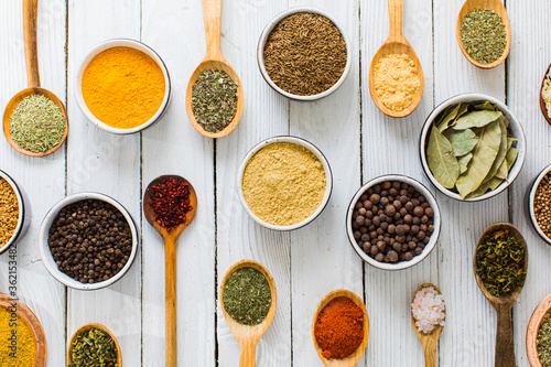 Assorted colorful spices and herbs in bowls and spoons