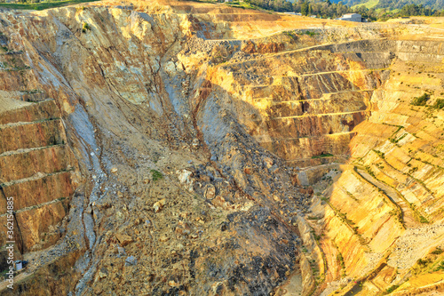 Open-cast gold mine, with terraces for transporting ore along the edges of the pit. One wall of the mine has collapsed in a rockslide. Martha Mine, Waihi, New Zealand