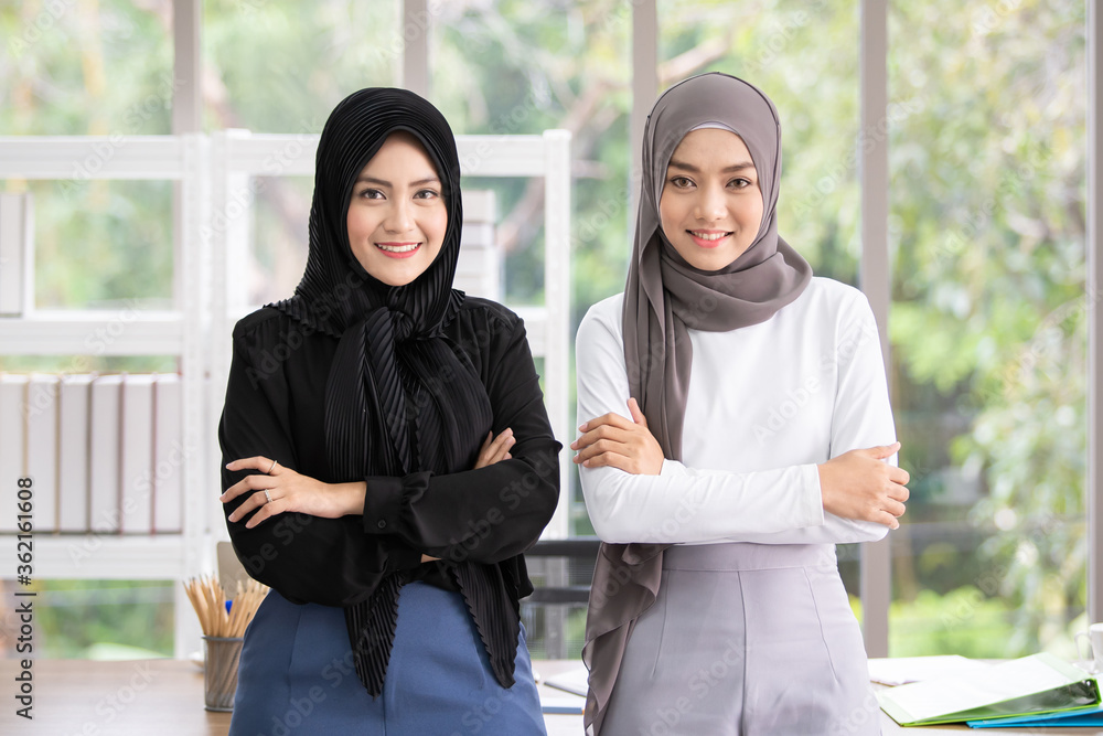 Two Asian Muslim businesswoman talking and working together in the office. Diversity in culture and gender concept. Two Asian Muslim businesswoman talking and working together in the office. Diversity in culture and gender concept.