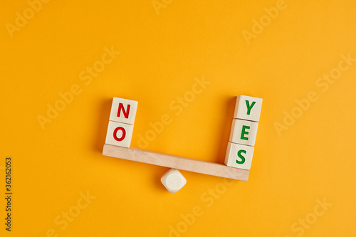 es and no inscription on wooden cubes on a seesaw with yes outweighs no