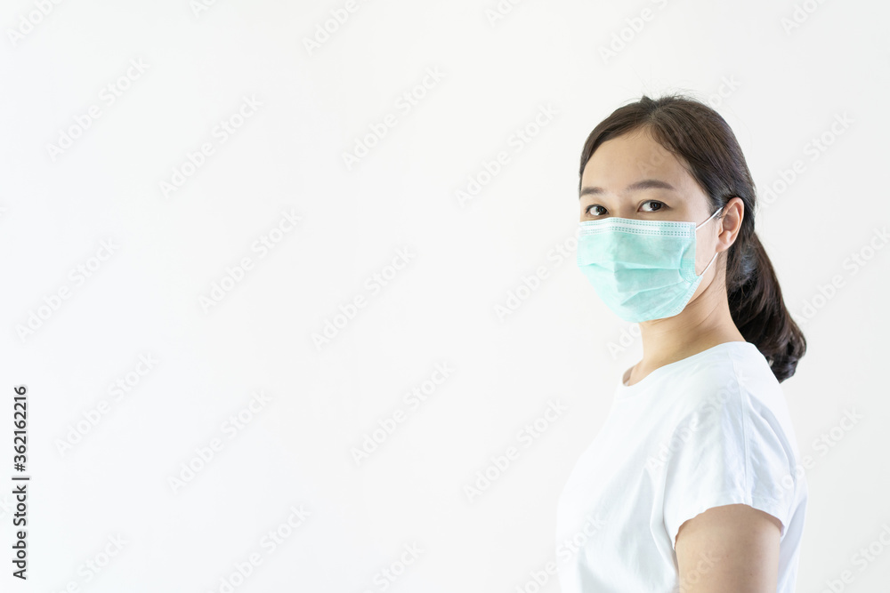 Asian young attractive woman wearing a protective hygiene mask over her face to protect flu and virus. Unwell influenza in infected woman portrait with yellow background. Covid19 and Coronavirus. Asian young attractive woman wearing a protective hygiene mask over her face to protect flu and virus. Unwell influenza in infected woman portrait with yellow background. Covid19 and Coronavirus.
