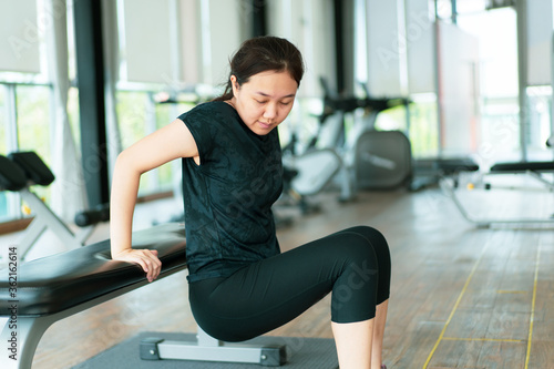 Strong young woman sports woman exercising in the indoor gym. Asia woman exercise tricep muscle by using dips up pose. Photograph with copy space.