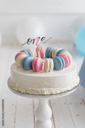 One-year-old children's cake decorated with pink and blue macaroons with number one topper on a white background. Beautiful birthday cake for a child.