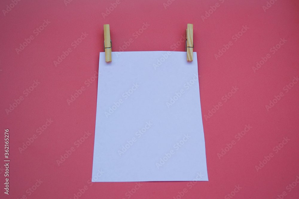 simple wooden clothespins hold a white sheet of paper on a pink background for the ad simple wooden clothespins hold a white sheet of paper on a pink background for the ad