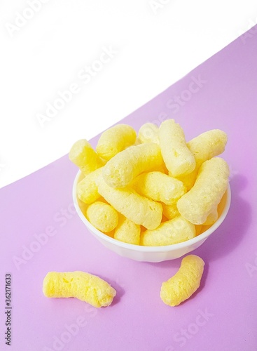 Yellow corn sticks in a white plate on a purple background.