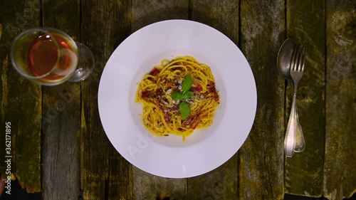 Pasta Carbonara. Spaghetti with bacon, parmesan cheese, and basil leaf. Pasta Carbonara on a white plate with parmesan on a dark background. Italian food concept. Overhead view.
