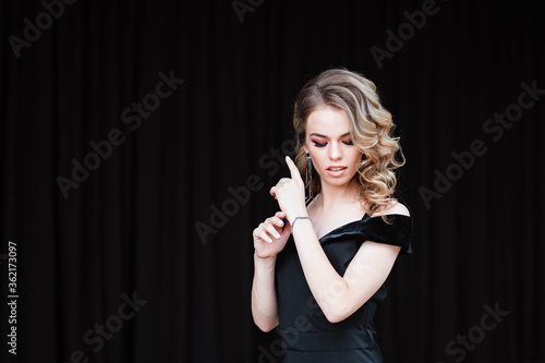 Beautiful blonde, young girl. Portrait of a young girl in a restaurant. Young girl in a restaurant on a black background. Portrait of a girl in a black dress. Young girl.